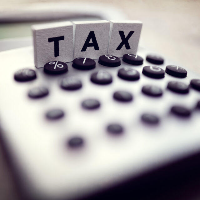 Calculator with the word tax written in wooden block letters